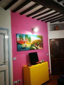 Habitación con una pared rosa y un ordenador en un armario amarillo. en ALLOGGIO S.ANNA en Isola del Giglio