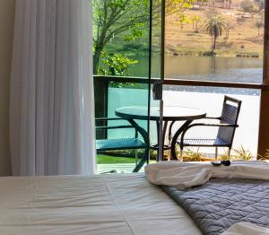 a bedroom with a bed and a view of a table at Escarpas Eco Village in Capitólio