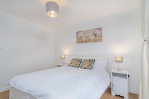 a bedroom with a white bed and two lamps at Kentmere Apartment Thamesmead in Thamesmead