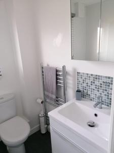 a white bathroom with a toilet and a sink at 1 Fulmar Road**Next to West Beach and Golf Course in Lossiemouth