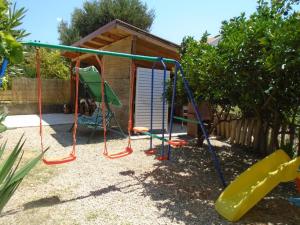 a playground with a slide and a swing at Apartments Vidic in Orebić