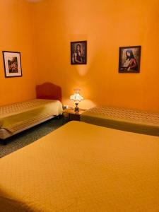2 letti in una camera con pareti arancioni di B&B Bruno a Cosenza