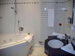 bagno con vasca, lavandino e doccia di Hotel Alexander a Oldenburg