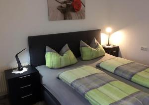 una camera con 2 letti con cuscini verdi di Ferienwohnung Angelika a Degerfelden