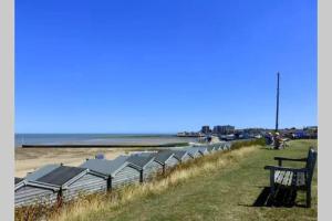 a bench sitting next to a beach with the water at Seven Seas Beach Retreat Studio Flat in Birchington