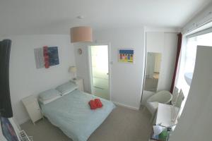 Dormitorio pequeño con cama y espejo en Seven Seas Beach Retreat Studio Flat, en Birchington