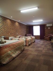 a room with four beds and a brick wall at Cobar Town & Country Motor Inn in Cobar