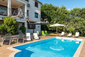 a swimming pool with chairs and umbrellas next to a building at Apartments Villa Verde-Adults Only in Mušalež