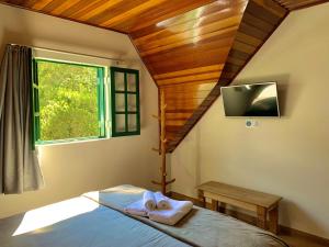1 dormitorio con 1 cama con toallas y ventana en Castelo Piazzale - Campos do Jordao, en Campos do Jordão
