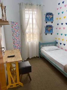 a bedroom with a bed and a desk and a window at Pousada Santa Lolla in São Carlos