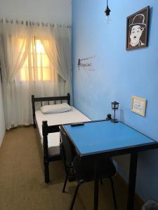 Cette chambre comprend une table, un lit et un bureau. dans l'établissement Pousada Santa Lolla, à São Carlos