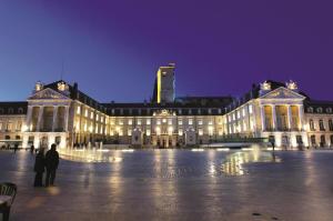 um grande edifício com pessoas de pé na frente dele à noite em Le paradis iyedessil em Dijon