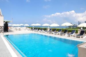 ein Schwimmbad mit Stühlen und Sonnenschirmen auf einem Gebäude in der Unterkunft Flipper Lodge Hotel - SHA Extra Plus in Pattaya