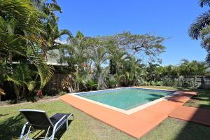 a swimming pool in a yard with two chairs at Pacific Reef by Kacys in Bargara