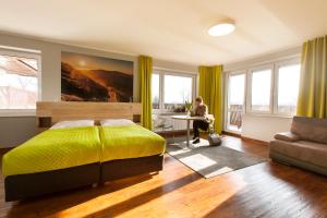 イェレニャ・グラにあるIdar Apartamentyのベッドルーム(黄色いベッド1台、テーブルに座った人付)
