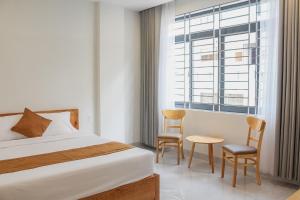 1 dormitorio con 1 cama, 2 sillas y ventana en Anh Đào Hotel en Vung Tau
