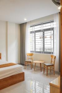 1 dormitorio con 1 cama, 2 sillas y mesa en Anh Đào Hotel en Vung Tau