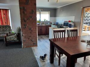 a living room with a table and a kitchen at Papamoa Budget Accommodation in Papamoa