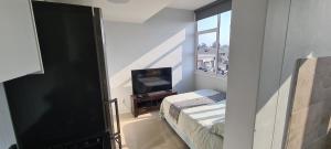 Habitación con TV, cama y ventana. en Modern apartments at CZ KUBS, en East London