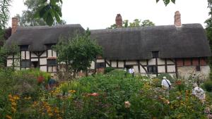 an old house with a thatched roof in a garden at Cottage 5 minutes walk to river and town centre in Stratford-upon-Avon