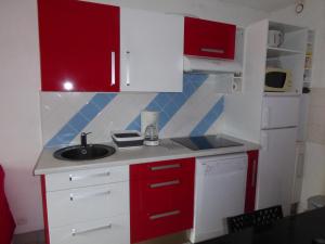 a small kitchen with red cabinets and a sink at à la montagne en famille App106 in Cauterets