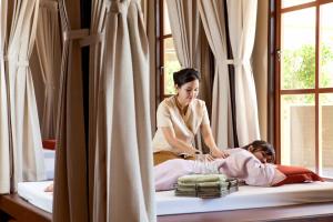 a woman lighting candles on a little girl on a bed at Mountain Creek Golf Resort & Residences in Si Khio