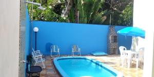 a pool with a blue wall and chairs and an umbrella at Maragogi Praia dos Corais in Maragogi