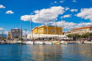 a group of boats docked in a harbor with a yellow building at Apartman Altamar Rijeka in Rijeka