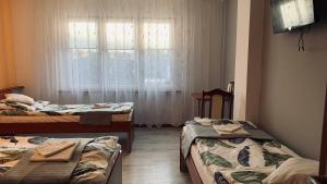 Zimmer mit 3 Betten und einem Fenster in der Unterkunft Bianco - pokoje noclegowe in Częstochowa