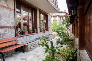 a bench sitting outside of a building with potted plants at Guest House Ilinden in Bansko