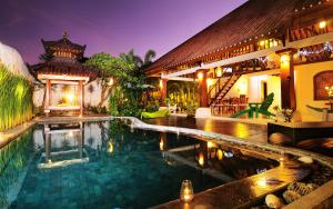a swimming pool in front of a house at Villa Domus De Janas in Seminyak