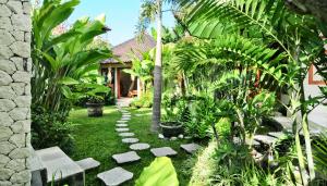 a garden with a palm tree and some plants at Villa Domus De Janas in Seminyak