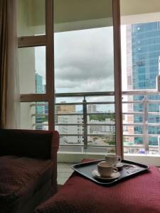 a tray with two coffee cups on a table in front of a window at StayInn Gateway Hotel Apartment in Kuching