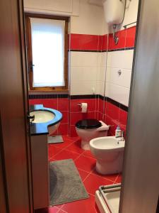 un bagno rosso e bianco con due servizi igienici e un lavandino di Appartamento laurentum a Torvaianica