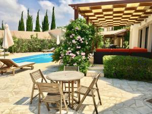 een patio met een tafel en stoelen naast een zwembad bij Villa Panorama - Stunning views in villa with hot tub, pool, garden in Kouklia