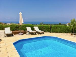 a swimming pool with two chairs and an umbrella at Villa Panorama - Stunning views in villa with hot tub, pool, garden in Kouklia