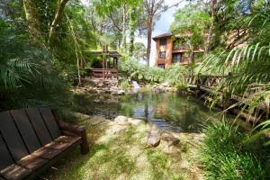 ein Haus neben einem Teich mit einer Bank in der Unterkunft Resort com Natureza no Centro in Gramado