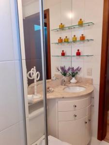 uma casa de banho com um lavatório e uma cabina de duche em vidro. em Resort com Natureza no Centro em Gramado