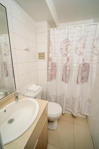 a bathroom with a sink and a toilet and a shower curtain at Departamentos Alpro Cavancha Vista a la Playa in Iquique