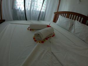 a white bed with two rolled towels on it at kome-Maya garden in Jambiani