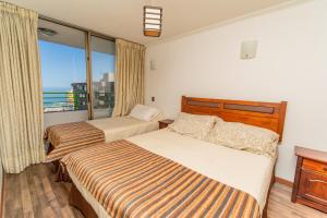 a hotel room with two beds and a balcony at Departamentos Alpro Cavancha Vista a la Playa in Iquique