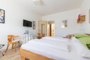 a bedroom with two white beds and a table at Pension Tadtendrang in Tadten