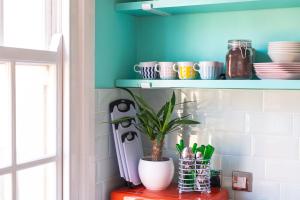 a shelf with a plant on a red table in a kitchen at The Courtyard Suite by Margate Suites in Margate +2 photos