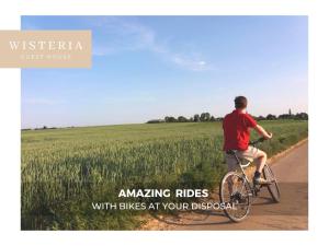 a man riding a bike down a road next to a field at Wisteria Guest House in Villers-lʼÉvêque
