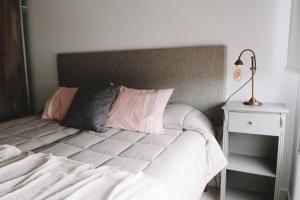 a bed with white sheets and pink pillows next to a table at Administración MAIPU 3 C DEPTO PREMIUM in Tandil