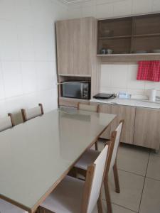 a kitchen with a table and chairs and a microwave at Apartamento Espaçoso Renato Maia in Guarulhos