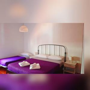 duas camas num quarto com lençóis roxos e sapatos em Vista Guapa em Jerez de la Frontera