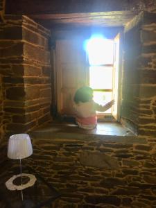 Un niño está mirando por una puerta abierta en Casa Ferreiro - Campo da Cruz - Lugo, en Baltar