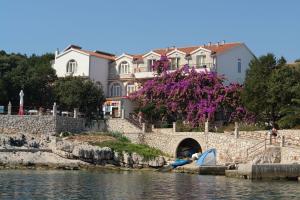 a house on the side of a river with a boat at Apartments Nikola 5m from beach in Selca kod Bogomolja