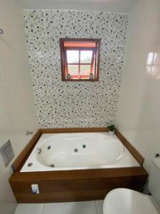 une baignoire dans une salle de bain avec une fenêtre dans l'établissement Recanto da Paz Ibitipoca com Hidromassagem, à Conceição da Ibitipoca